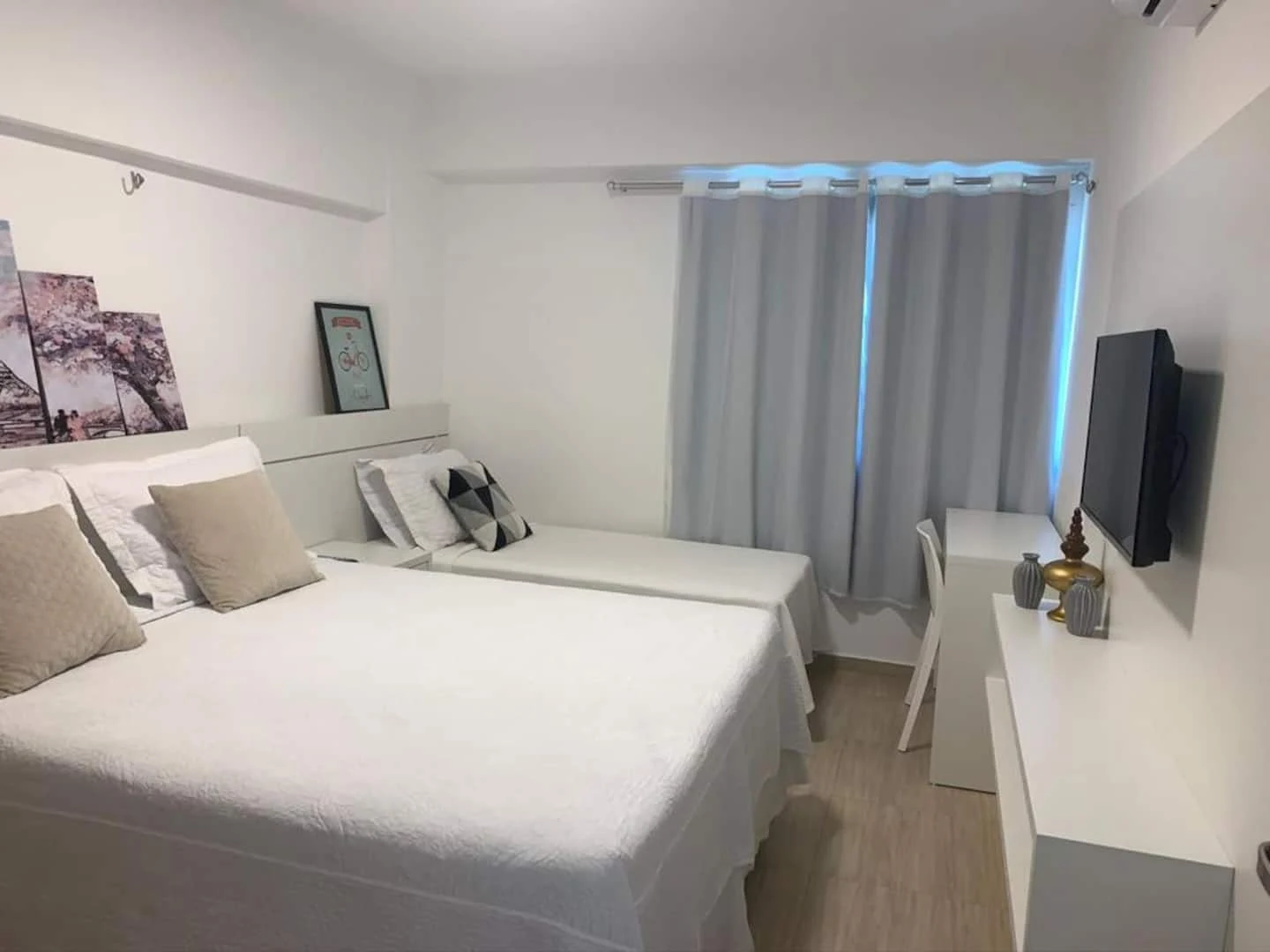 Quarto com cama de casal e cama de solteiro, em tons claros